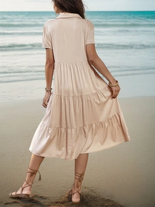 Close-up of peach short-sleeve shirt dress with tiered skirt on a sunny beach