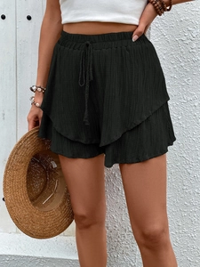 Detail of black tiered ruffled shorts with textured fabric and drawstring waist
