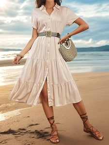 Detail of a tiered pink short-sleeved dress with a woven belt on a sunny beach