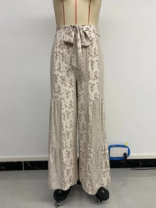 Detail of women's floral and geometric print wide-leg pants with a tie-waist band.