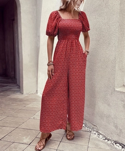 Detail view of red floral jumpsuit featuring a smocked square neck and puffy short sleeves