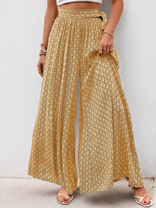 Detailed close-up of high-waisted wide-leg summer pants with geometric mustard print and belt