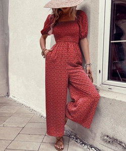 Detail of red floral bohemian jumpsuit featuring square neck smocked bodice and puff sleeves