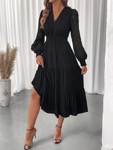 Detail of V-neck lace dress with semi-transparent long sleeves and tiered cake skirt