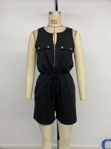 Detail view of black utility romper featuring drawstring waist and metal button pockets