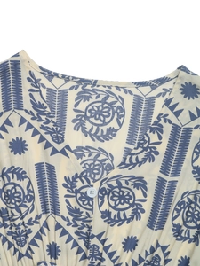 Detail of V-neckline with ethnic floral print and white button on woven fabric