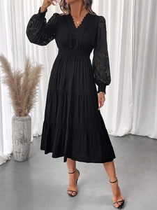 Detailed close-up of V-neck lace patchwork and textured floral sleeves on a black dress