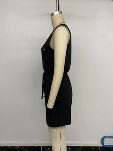 Detail of black sleeveless romper featuring a drawstring waist and silver button pocket
