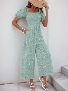 Detailed view of green floral romper with square neckline and puff sleeves in sun