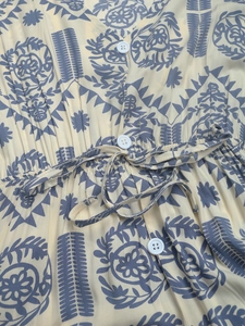 Detail of ethnic print dress with V-neck, white buttons and adjustable drawstring waist