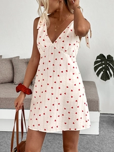 Close-up of white summer dress with red heart print and shoulder tie ribbons