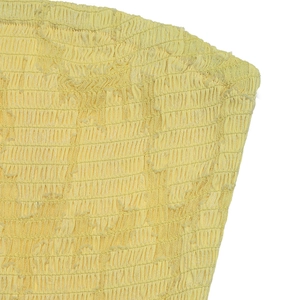 Detail von hellgelbem gerafftem Stoff mit Jacquard-Textur und zarten floralen Fransen