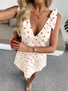 Detailed close-up of off-white mini dress featuring red heart print and bow shoulder straps
