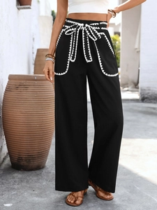 Detail of high waist black wide-leg pants with white lace trim and drawstring waist