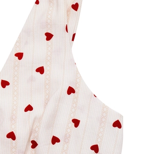 Detail of white summer dress fabric with red heart pattern and lace texture