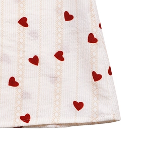 Close-up of white jacquard fabric with red heart prints and fine stitching detail
