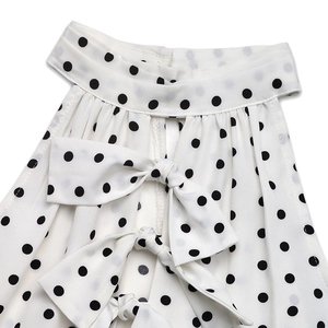 Detailed view of white polka dot dress with elegant bow tie back and chiffon fabric texture