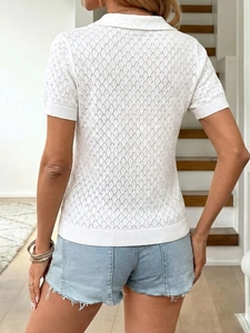 Détail d'un polo en maille blanche avec motif losange ajouré et manches courtes