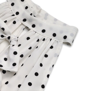 Detail of white polka dot dress featuring a halter neck and side bow tie ribbon