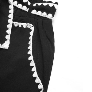 Detail showing high-waist black trousers with white crochet lace trim on the side pocket