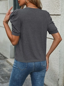 Women's dark grey puff sleeve T-shirt styled with classic blue jeans against grey wall
