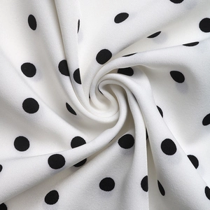Macro detail of breathable white summer dress fabric featuring classic black polka dot pattern