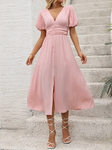 Détail de robe rose à col en V avec des plis à la taille et des boutons assortis