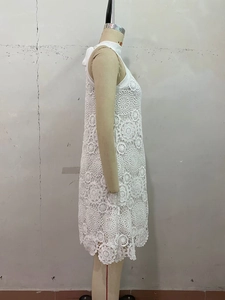 Detail of white crochet lace dress featuring floral cutout patterns and high neckline