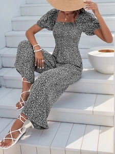 Detail of floral print jumpsuit with puff sleeves and pleated waist on white stairs
