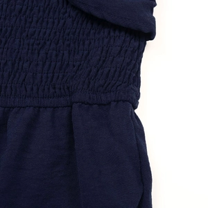Vue détaillée de la texture du tissu smocké bleu foncé sur une combinaison d'été