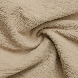Detailed macro shot of beige pleated crinkle fabric with soft texture and natural drape