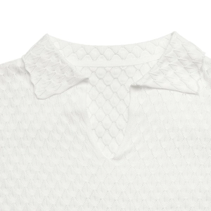 Détail d'un col polo blanc en tricot avec texture ajourée en losanges et décolleté en V