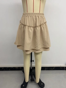 Detail view of the beige tiered mini skirt showing elastic waistband and ruffled texture