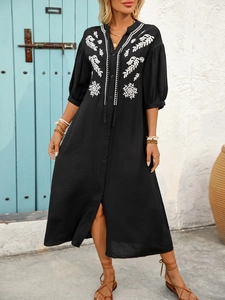 Detail of bohemian black maxi dress featuring white symmetric embroidery and V-neckline