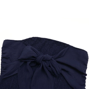 Détail du tissu smocké bleu marine et du nœud papillon décoratif sur la combinaison