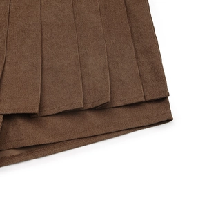 Detailed close-up of dark brown corduroy pleated skirt with fine texture and hem stitching