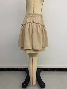 Detail of beige tiered ruffle mini skirt showing elastic waist and textured fabric