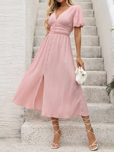 Détail d'une robe rose à col en V avec manches bouffantes, boutons et tissu texturé