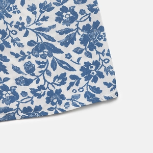 Detailed close-up of blue floral print fabric with clean hemline stitching on summer dress