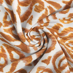 Detailaufnahme von orange-braunem Leopardenmuster-Stoff mit glatter Webstruktur