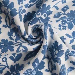 Detailed macro shot of blue floral pattern on white cotton fabric with woven texture