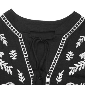 Close-up of V-neckline with delicate white embroidery and tassel ties on black dress
