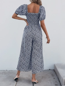 Back view of floral navy jumpsuit featuring smocked elastic waist and wide leg cut