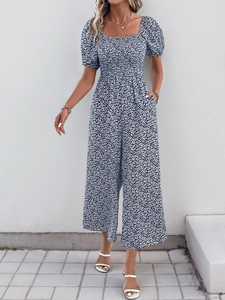 Detail of smocked waist and white floral print on navy blue short sleeve romper