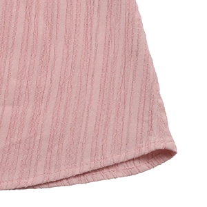 Gros plan détaillé du tissu plissé rose clair avec des coutures soignées sur la robe