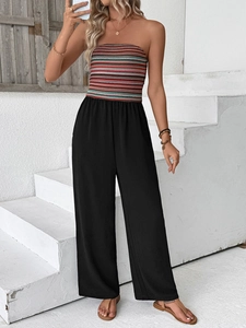 Detail van meerkleurige gestreepte strapless top met zwarte jumpsuit met wijde pijpen