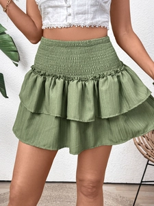 Detailed texture of sage green smocked waist and layered ruffle hem of the mini skirt