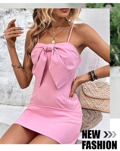 Detail of pink bodycon dress with oversized bow design and stylish gold jewelry