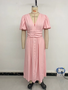 Détail de robe midi rose à col en V avec taille plissée et boutons sur le devant