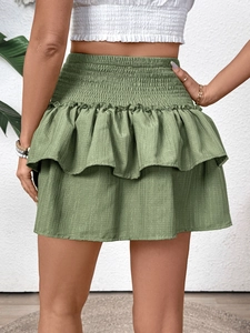Close-up of smocked high waist and layered ruffle details on a sage green mini skirt